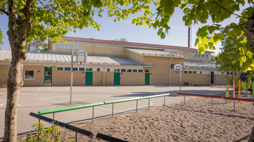 Gul idrottshall med basketkorgar vid Järlåsa skola