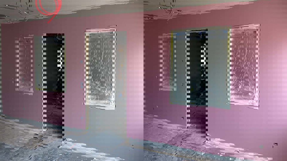 Nymålad rosa vägg i en inomhusmiljö som renoveras.