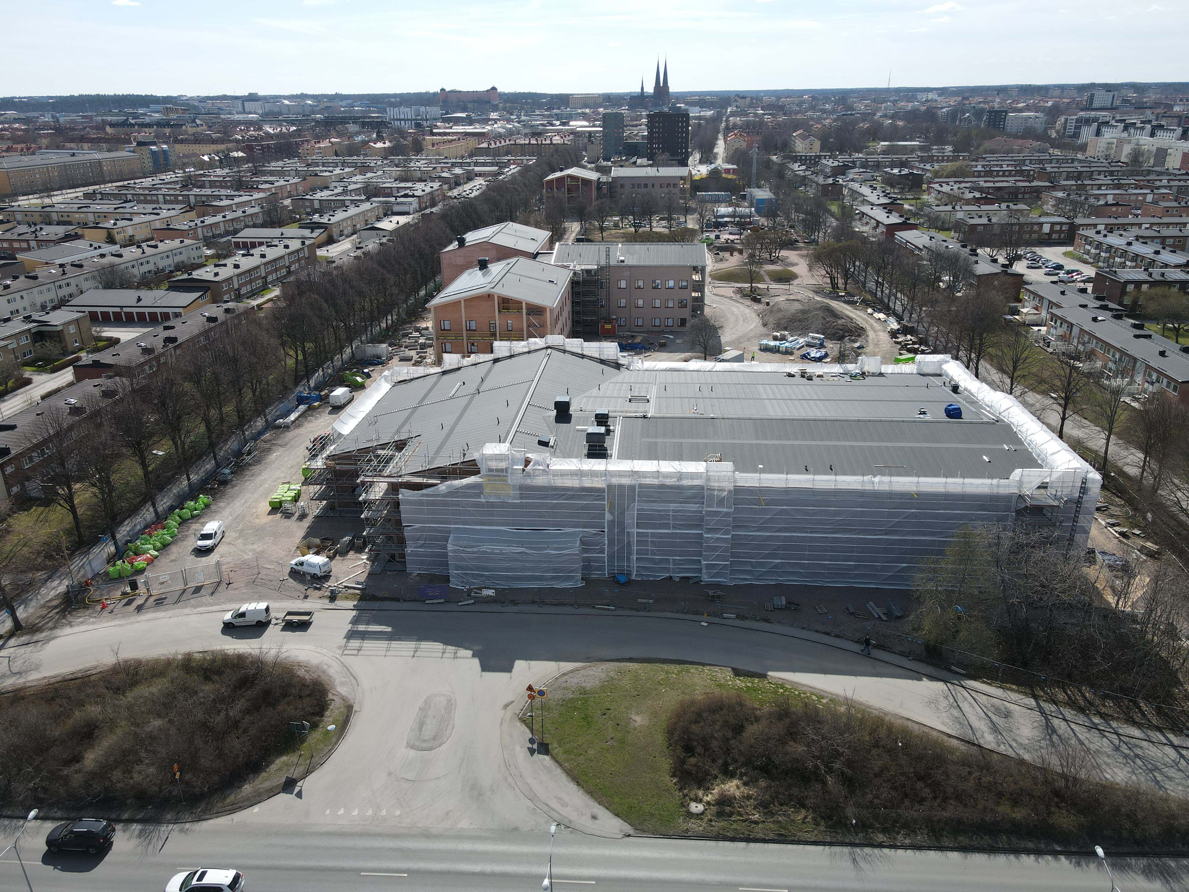Flygbild över byggplats med omgivande bebyggelse