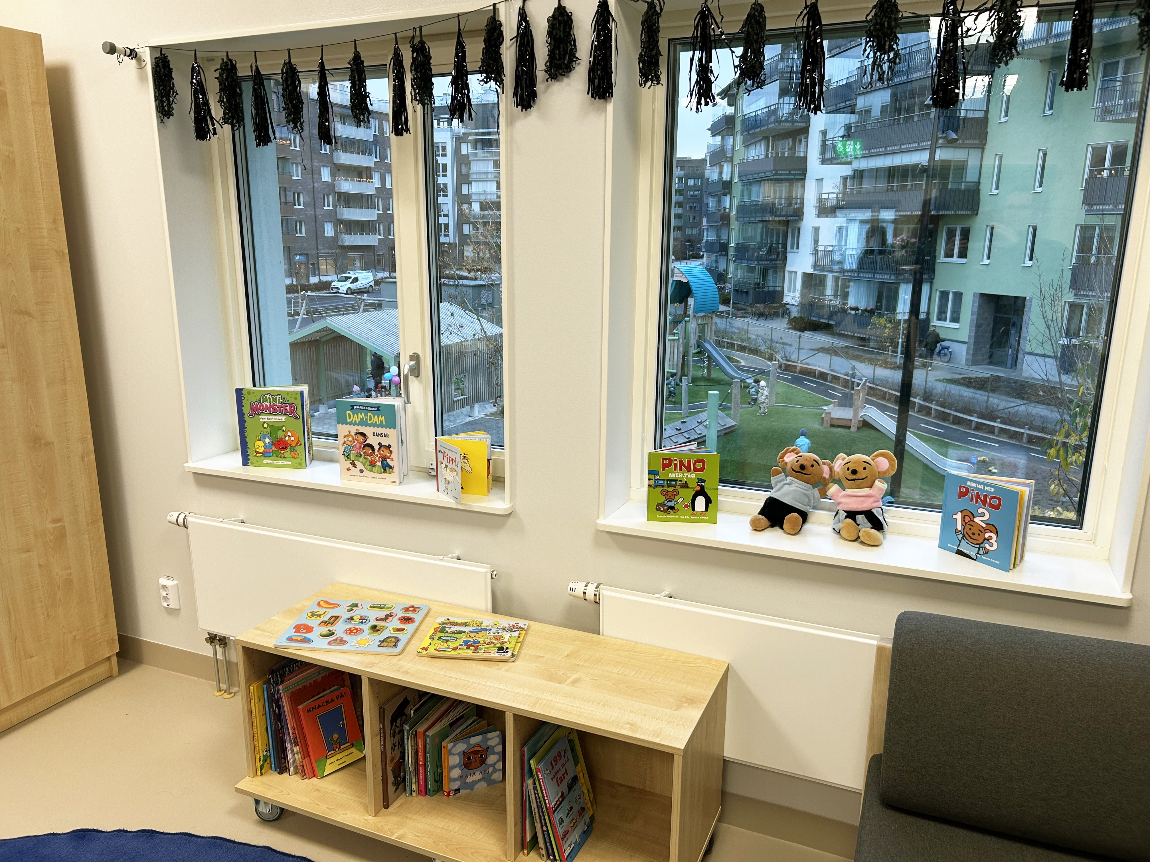 Ett klassrum med böcker och leksaker framför fönster som vetter mot en innergård.