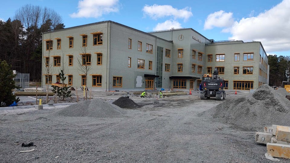 Grävmaskin på byggplats av skola