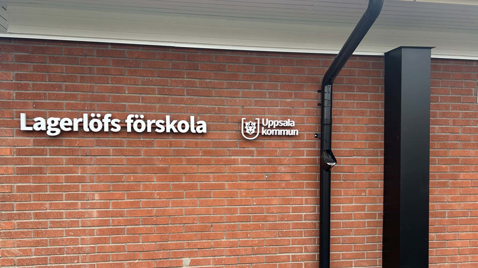 Brun tegelvägg med förskoleskylt.