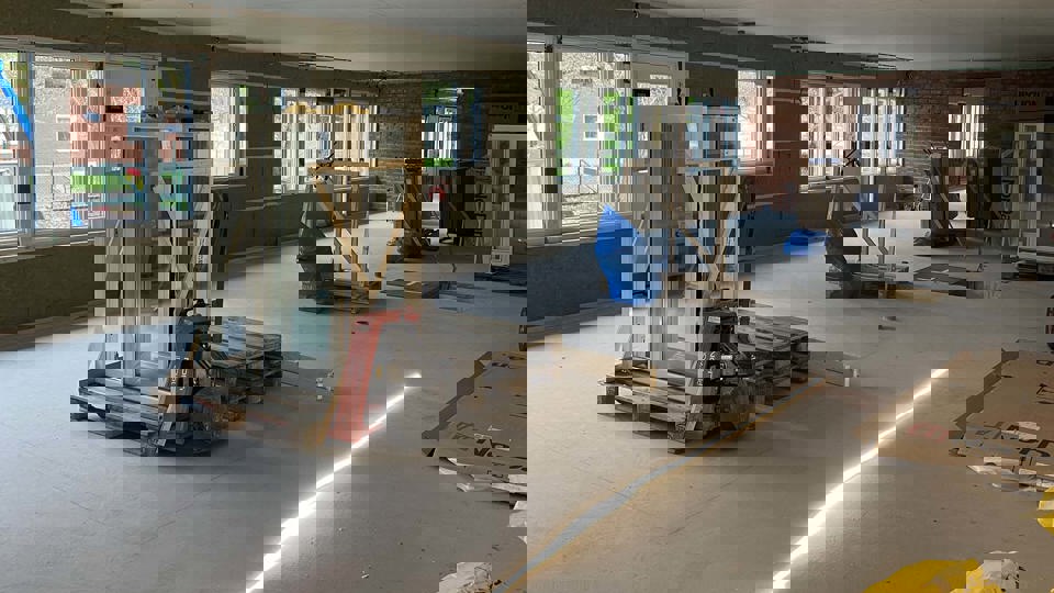 Uppställda glasfönster i ett rum som renoveras.