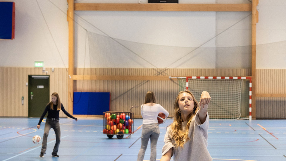 Flicka kastar en basketboll i en idrottshall.