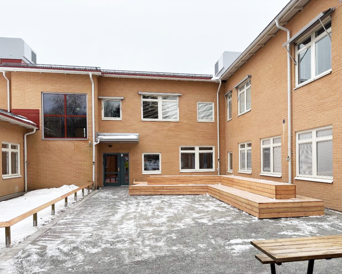 Nyrenoverad skolentré med bänkar i förgrund.