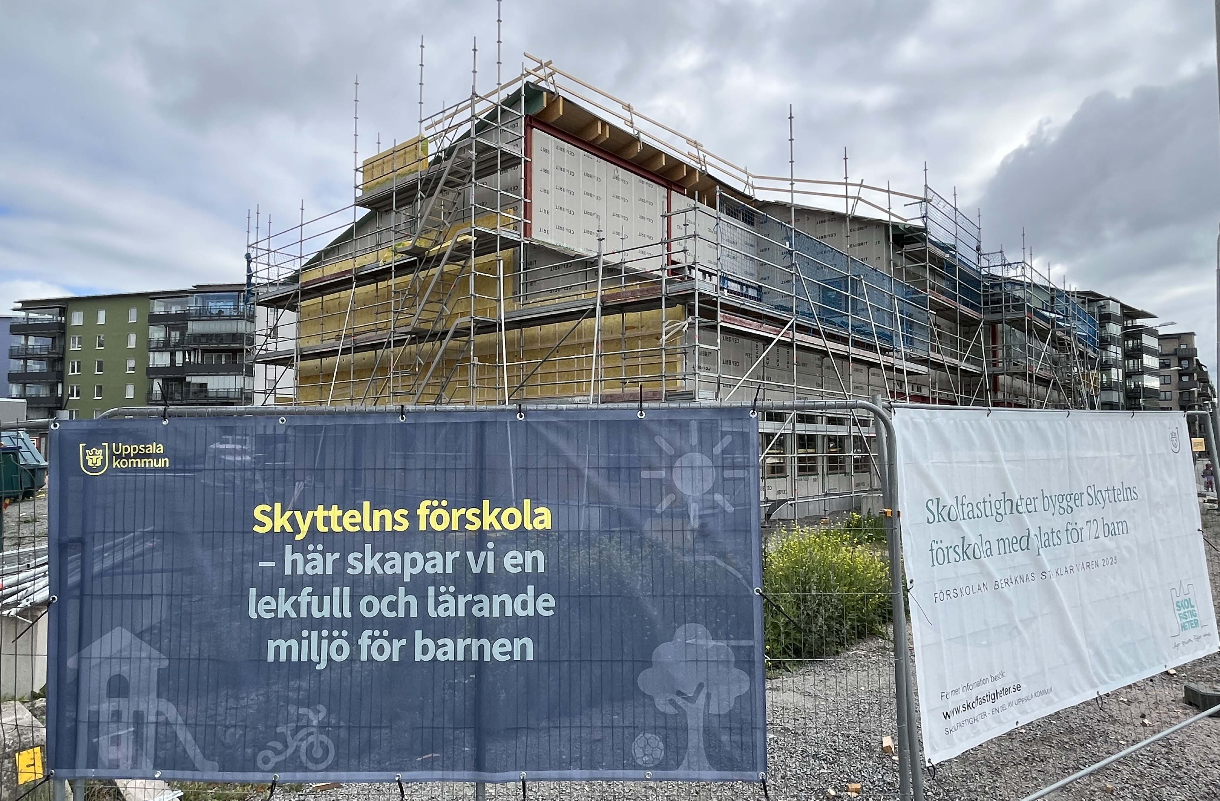 Byggplats för en ny förskola med vepor på stängsel i förgrunden.