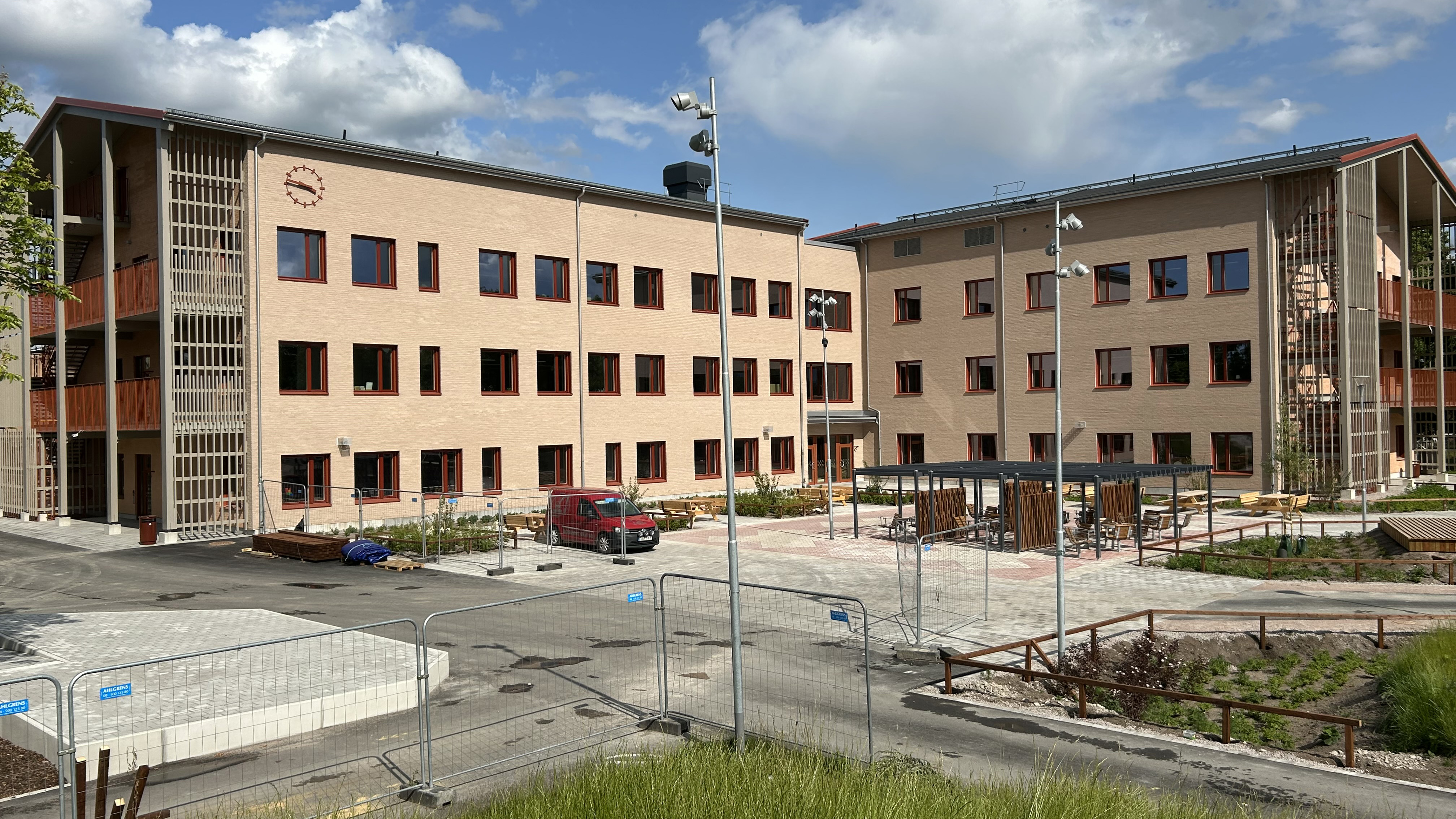 Nybyggd skola med ljusbrunt tegel och röda fönster.