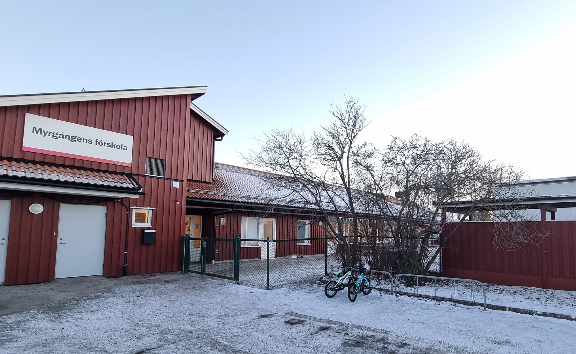 Röd förskolebyggnad med snö i förgrunden.