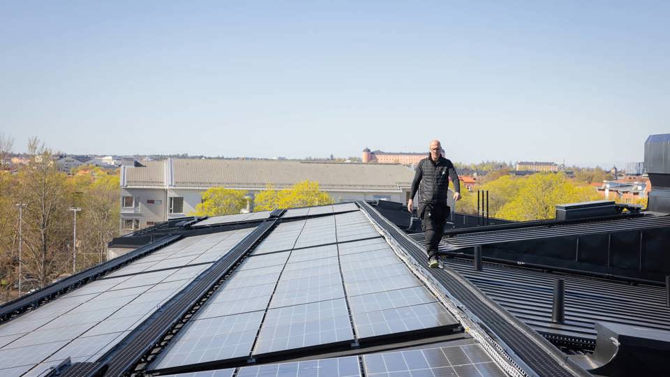 Drifttekniker som går på ett tak med solcellspaneler