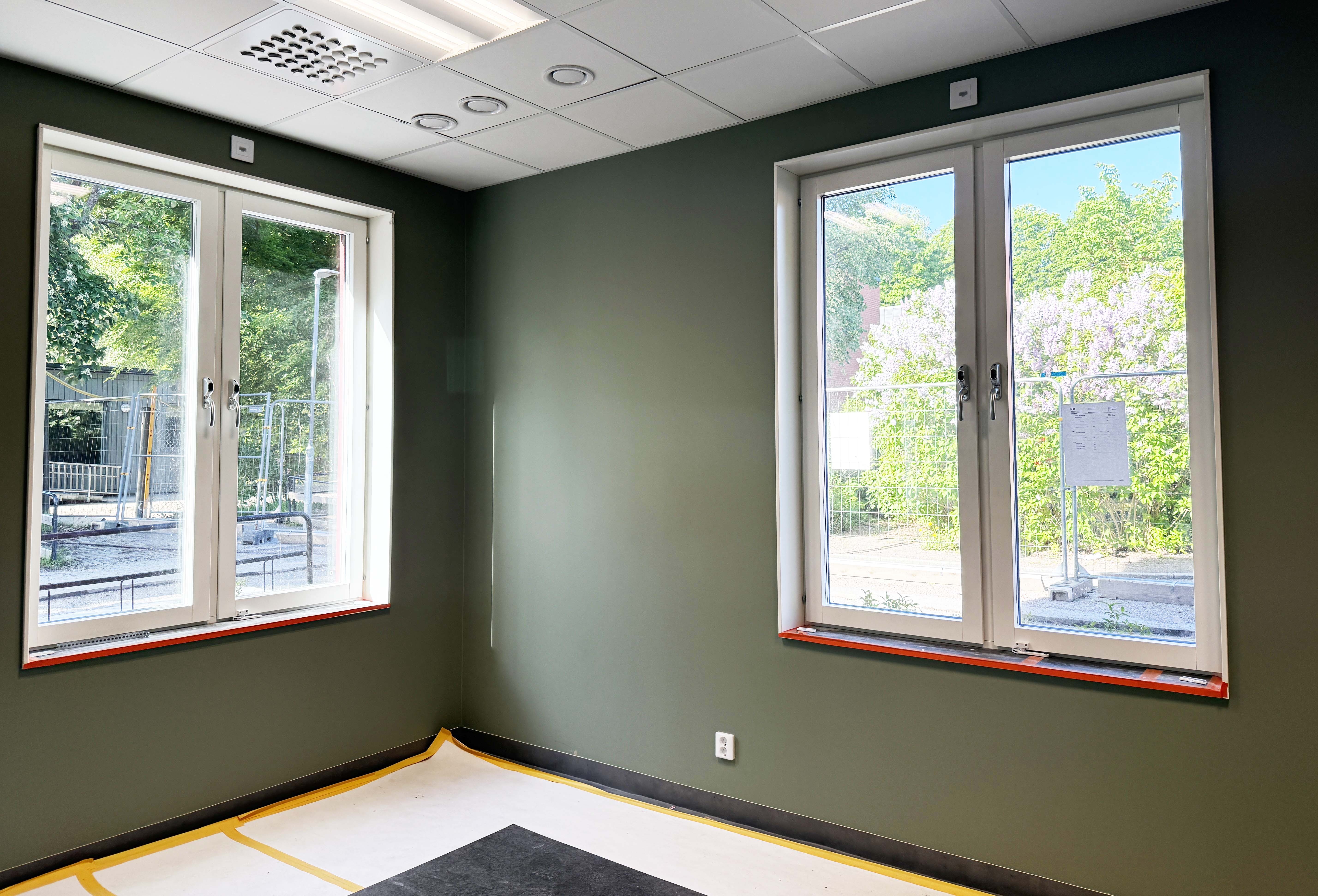 Grönmålat rum med fönster i en ny skola som håller på att färdigställas.