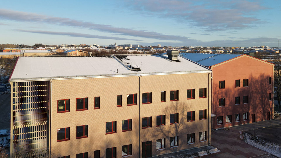 Snötäckt skolbyggnad i vintersol.