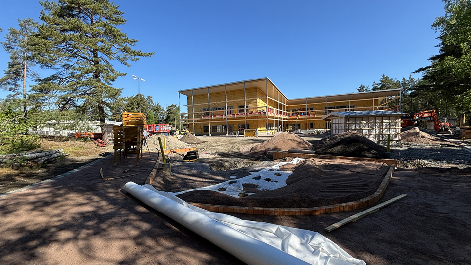 Byggplats där en ny förskola växer fram bredvid omgivande träd.