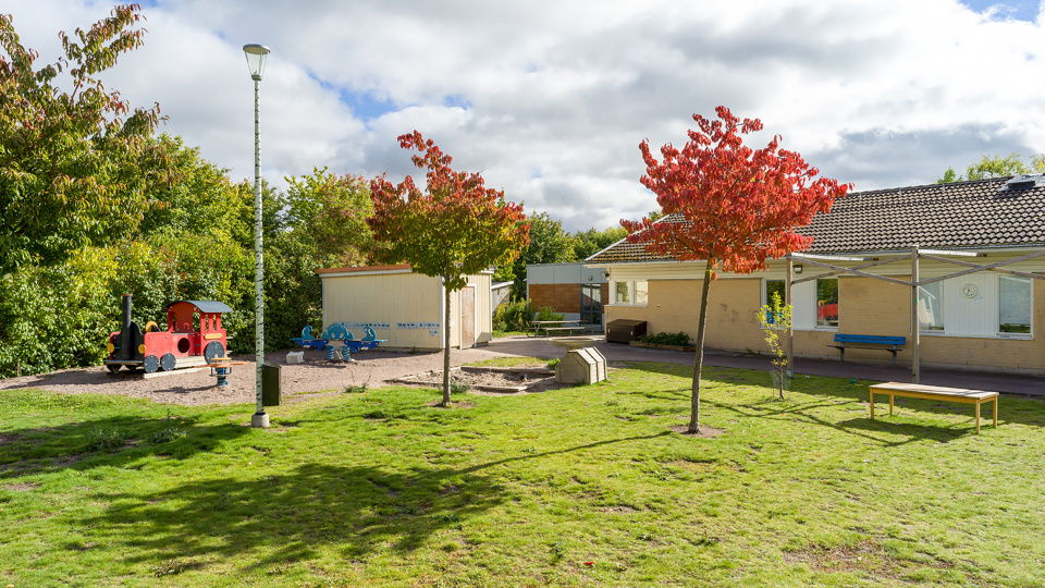 Voksenåsens förskolas skolgård och gula skolbyggnad